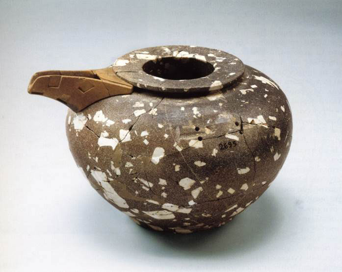 A stone bowl, brown with white flecks, with what looks like a beak stuck on the side