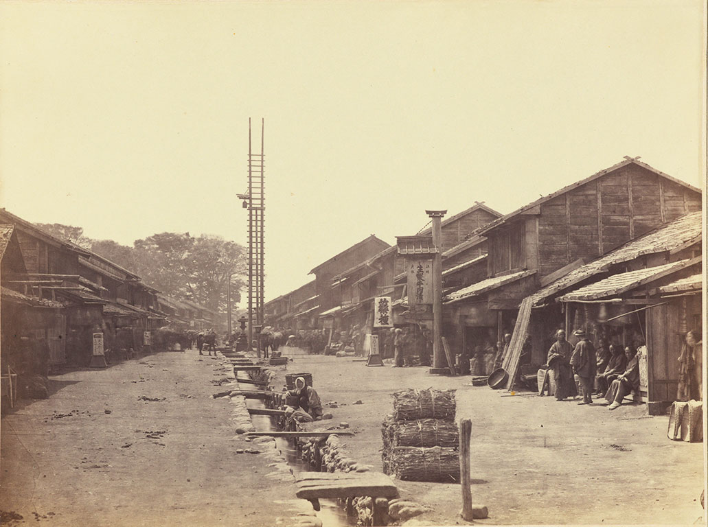 A street in a town, buildings on either side and a stone ditch in the center