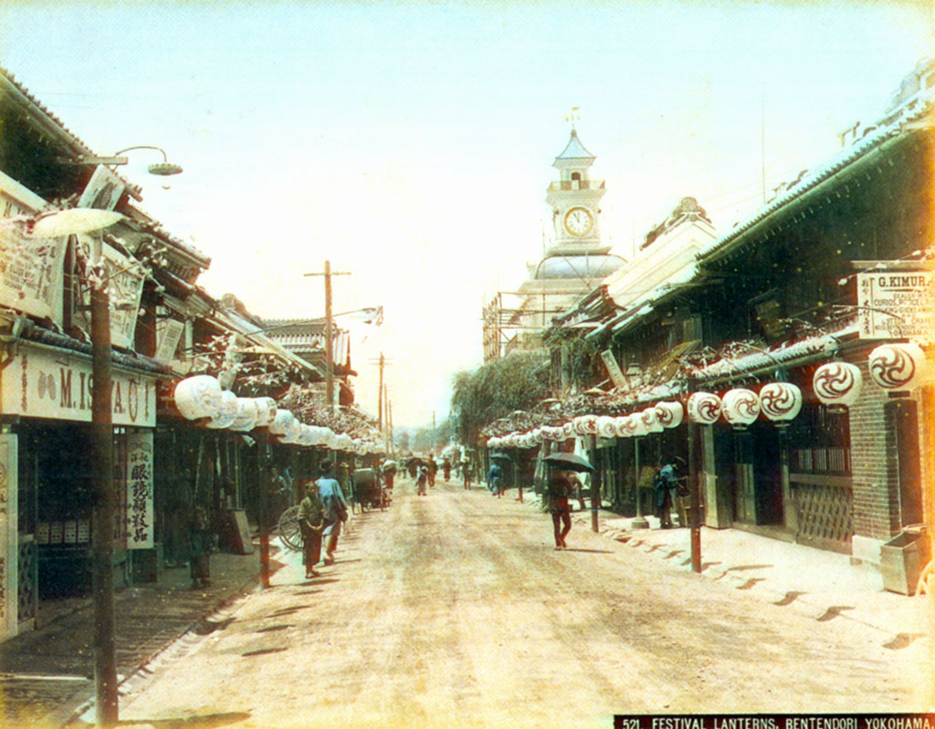 Street lined with paper lanterns, clock tower in the distance