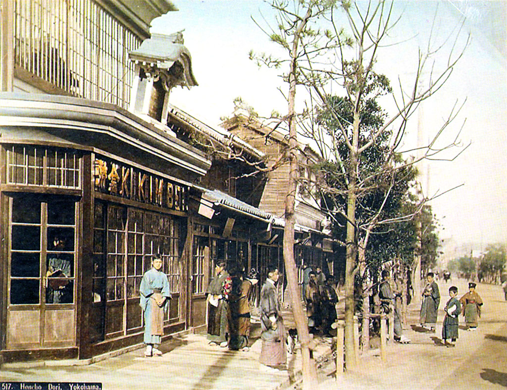 A street, buildings, a wooden sidewalk with people standing