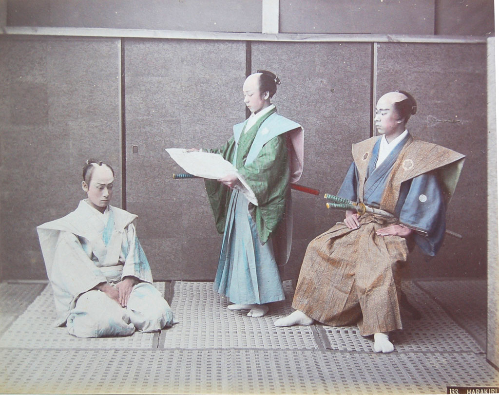 Tinted photograph, three men: on the left, a man kneeling, his eyes downcast; on the right, one man standing, reading from an open book, another man seated, both facing the kneeling man
