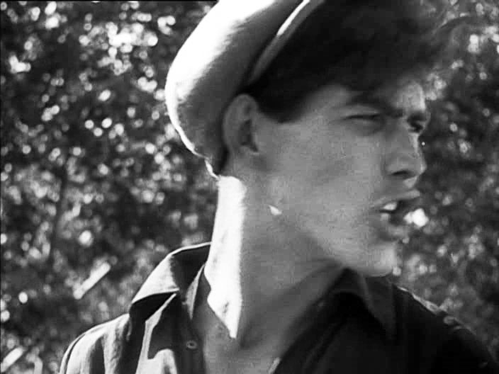 Movie still of young man in cap looking to the right and speaking