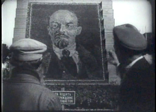 Two men regarding an image of Lenin