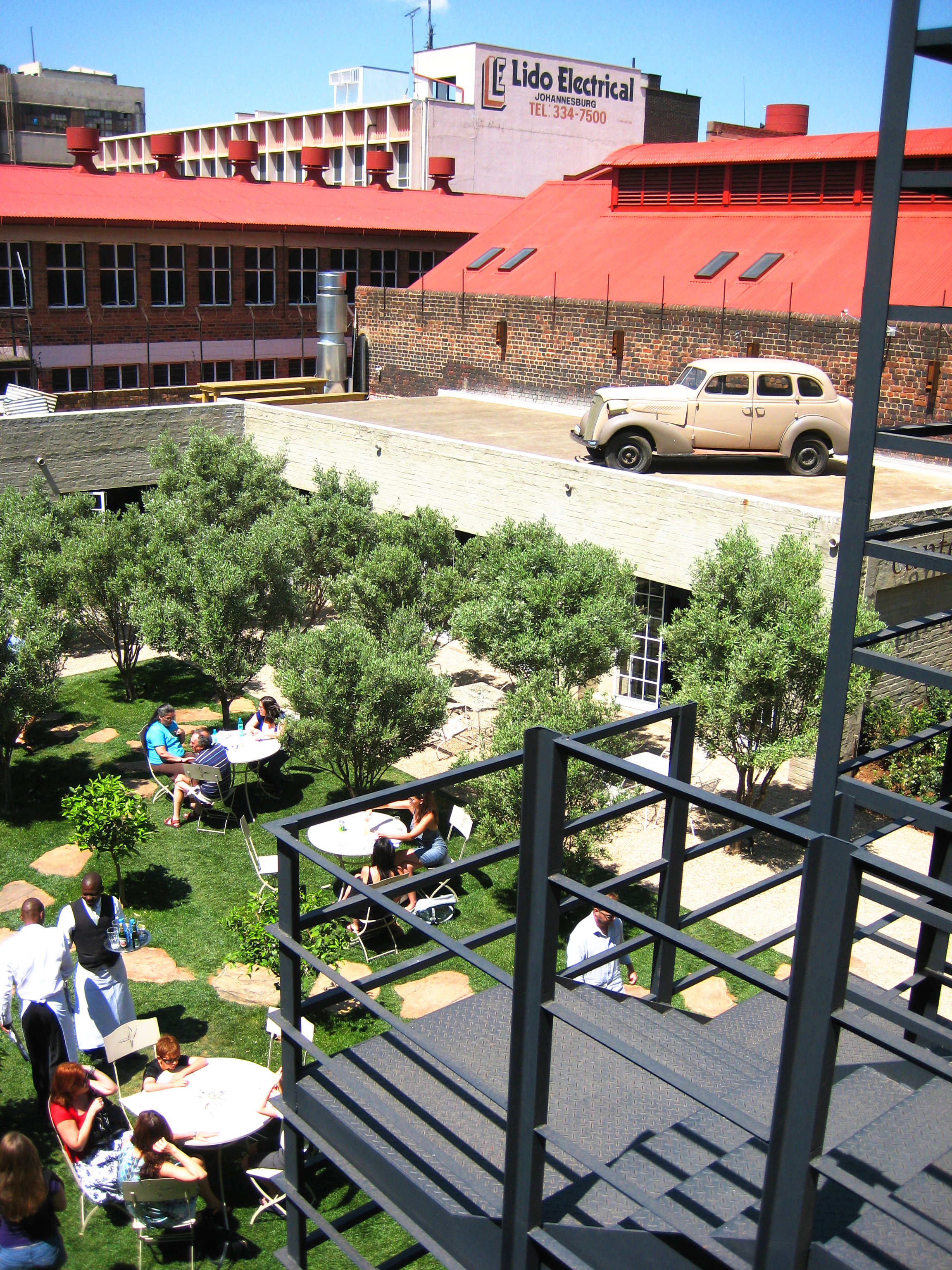 People sitting around small tables in a grassy courtyard
