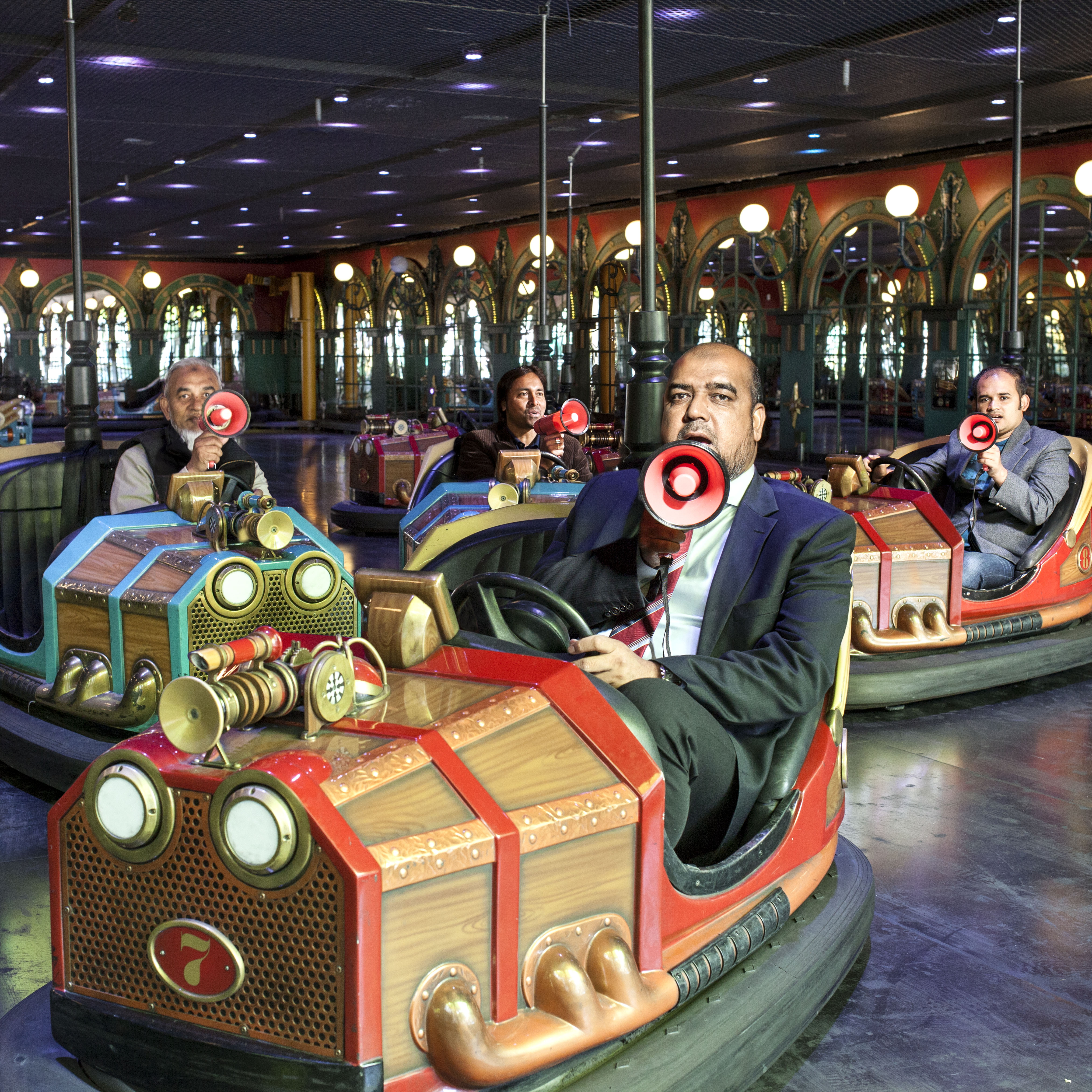 Immigrant men shouting into megaphones and sitting in bumper cars