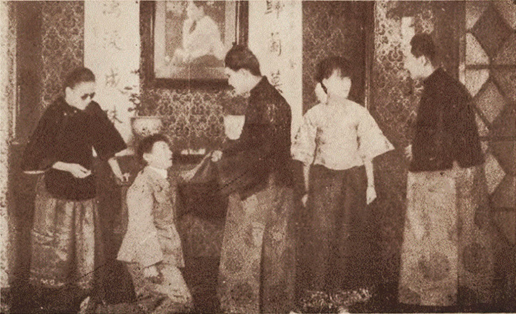 Four people standing, one on his knees beside a table